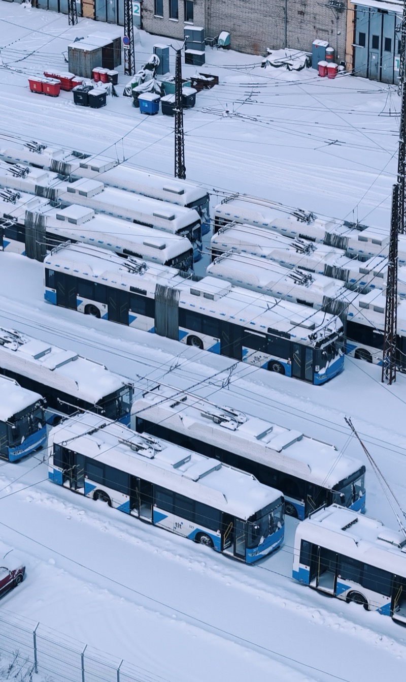 Blue and white trolleybuses in a snow-covered depot.