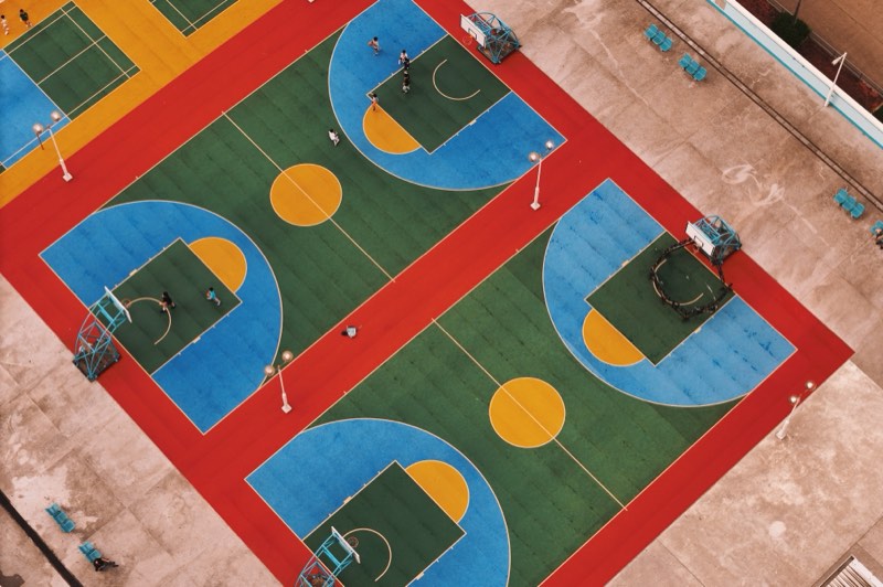 Colourful basketball courts on a rooftop, seen from above.