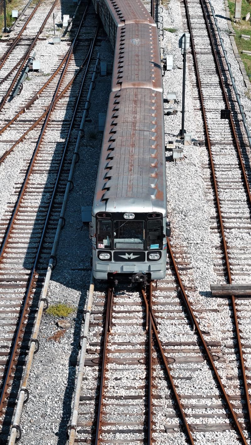 Grey metro train heading towards the camera on ballasted tracks, seen from above.