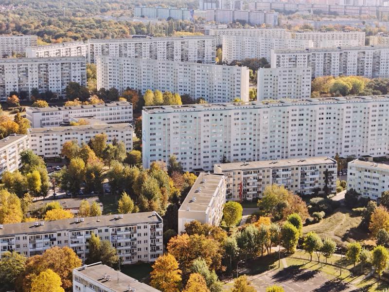 Large prefabricated housing estate among autumn trees, seen from above.