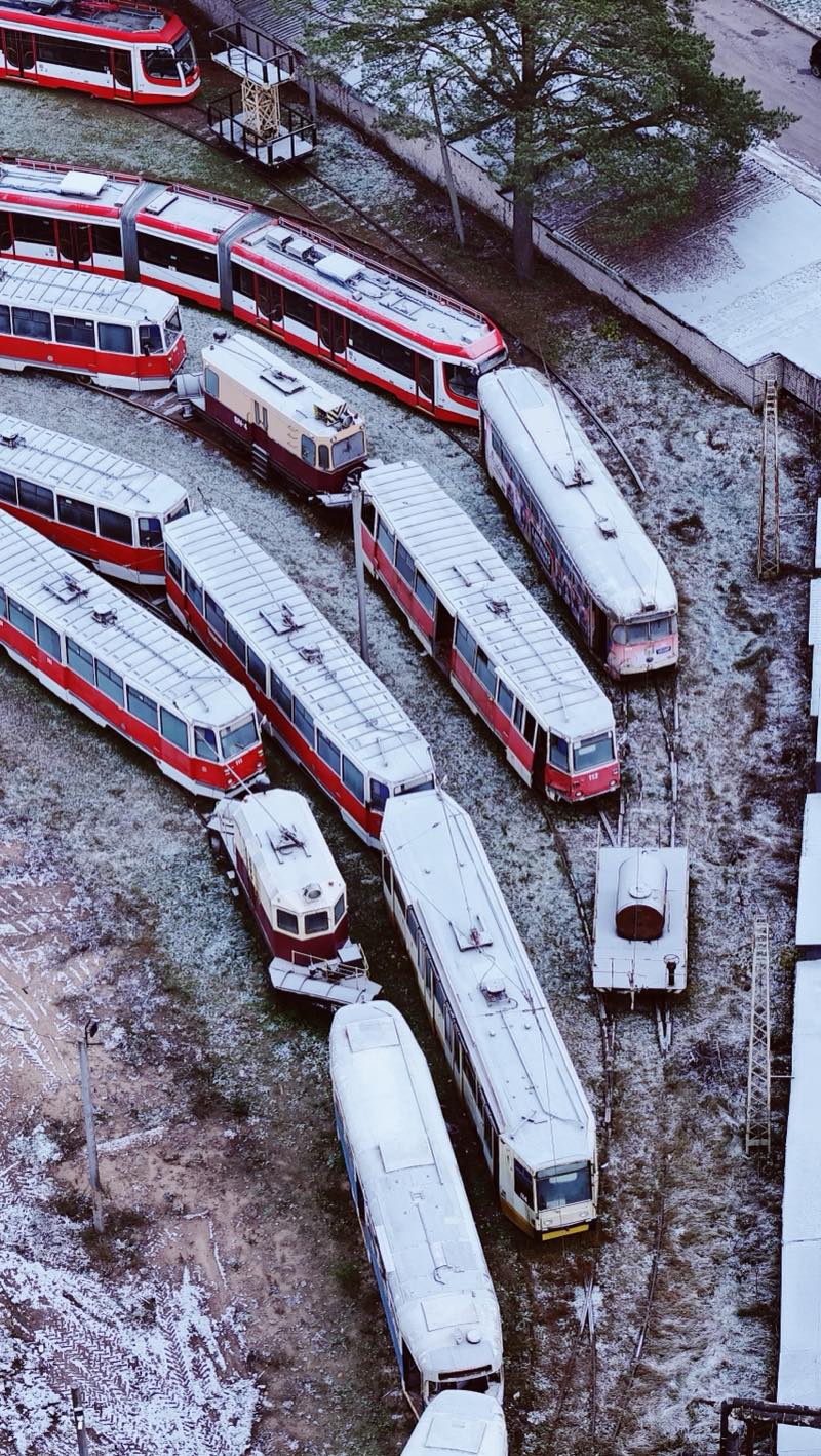 Red and white trams parked on curving tracks in light snow.