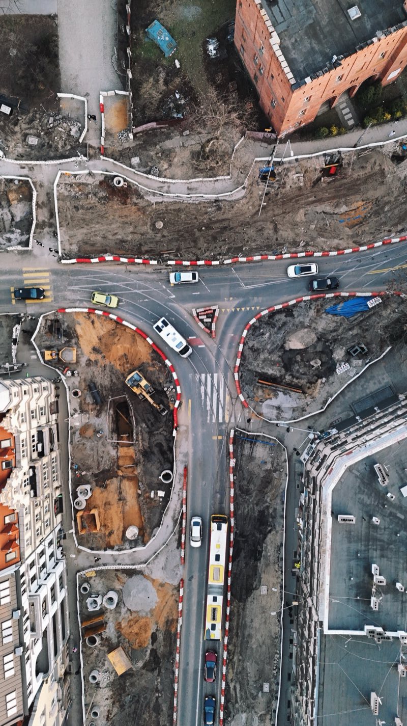 Top-down view of a city junction torn up for construction, with buses on the temporary road.