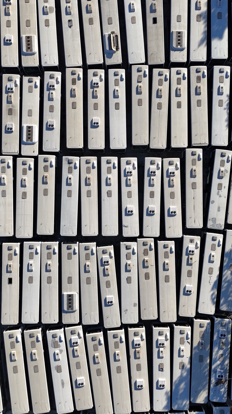 Top-down view of dozens of white bus roofs parked in tight rows.