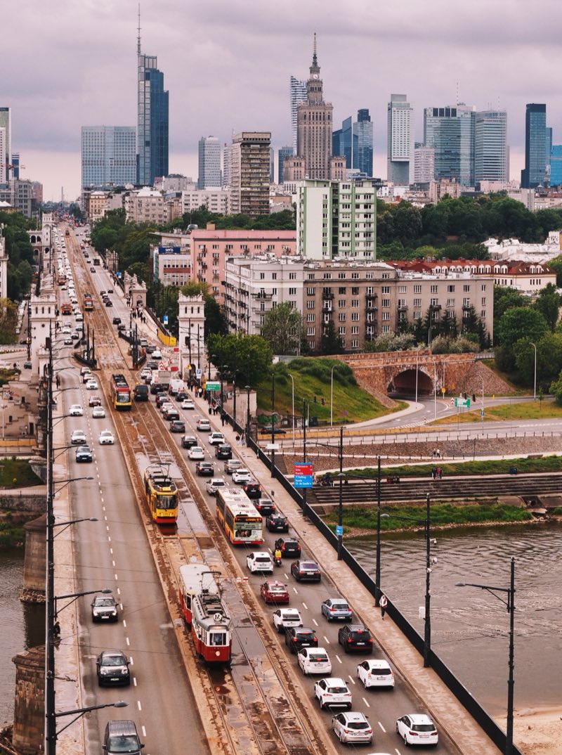 Trams and traffic on a long bridge into Warsaw, the Palace of Culture on the skyline.