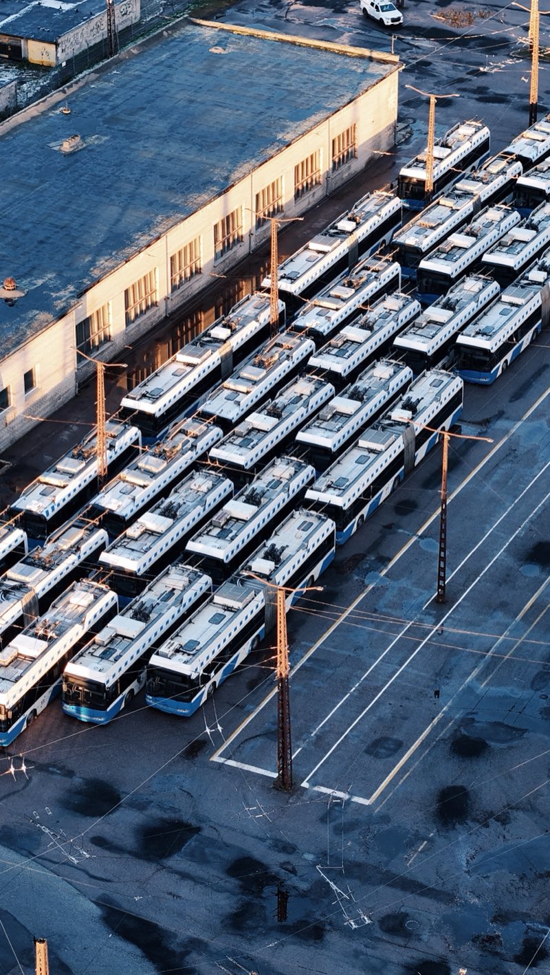 Trolleybuses parked in tight diagonal rows beside a depot building, seen from above.